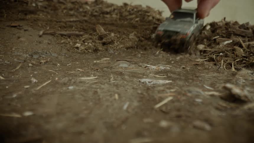 Hand with toy car passing through mud with water