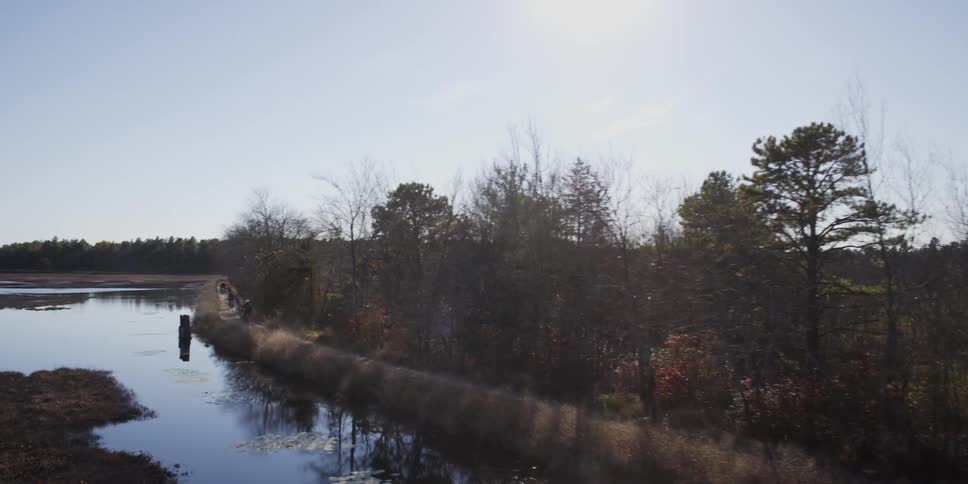 People ride dirt bikes near a lake