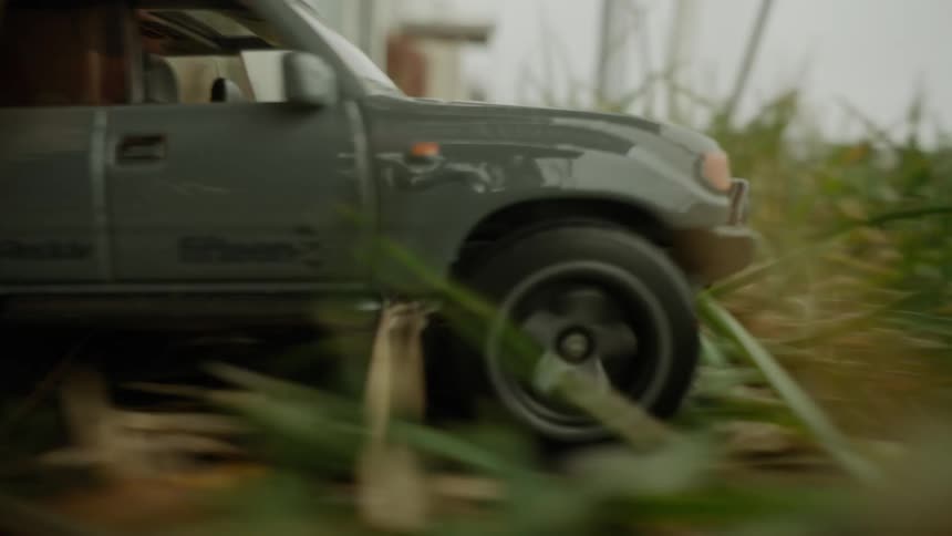 Close up of a hand pushing a toy car over green grass