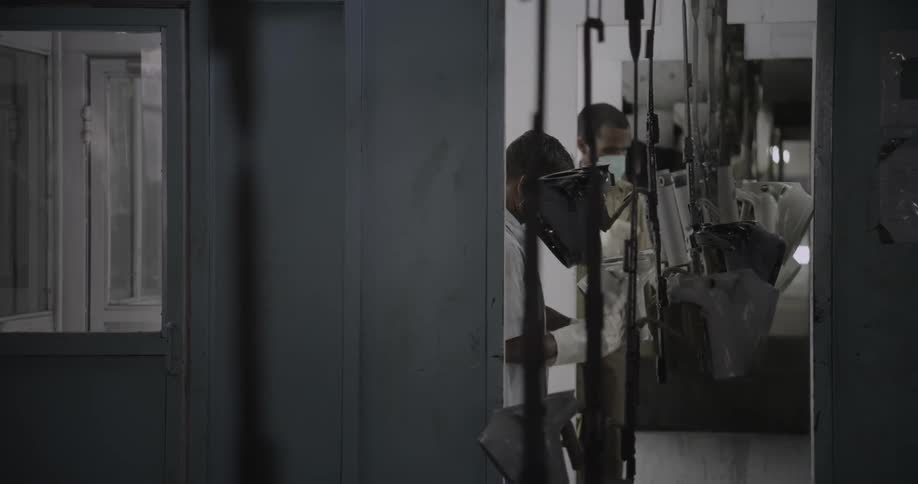 Factory workers wipe hanging parts