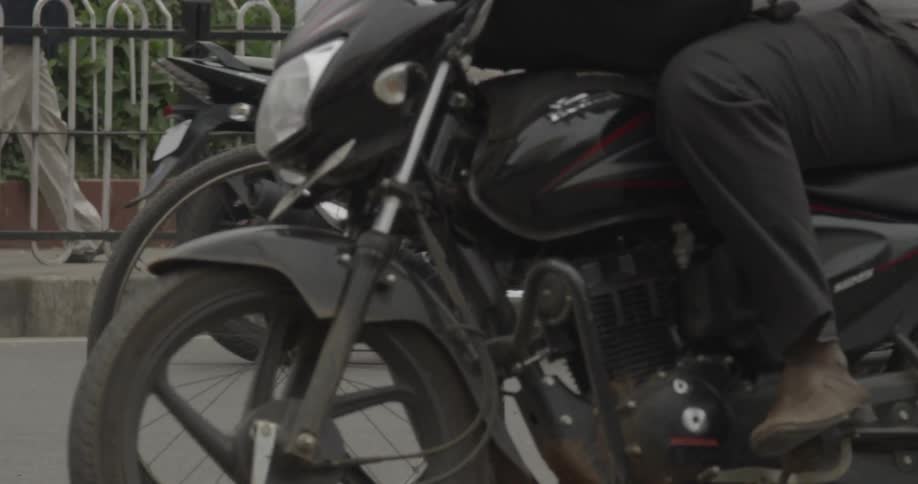 Close up of a bicyclist riding through a city street as scooters and motorcycles are there too
