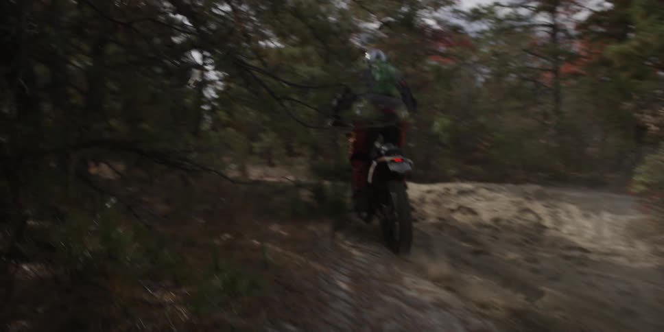 A dirt bike races off into the dirt trail