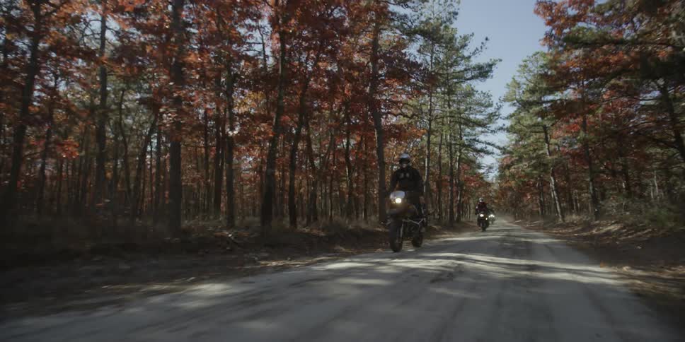 Motorcyclists ride on a dirt road in the woods