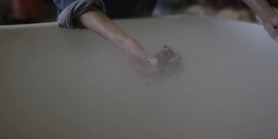 Person grabs something black and squishy from a tub