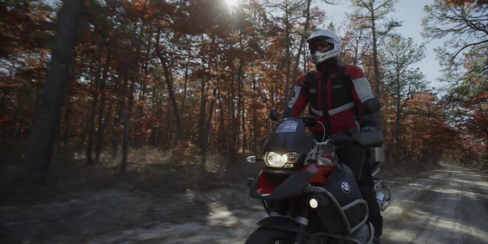 Person riding a motorcycle through the forest on a sunny day