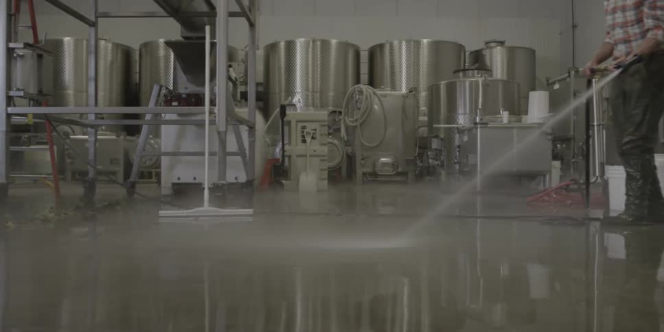Person hosing down a slick floor in some sort of factory