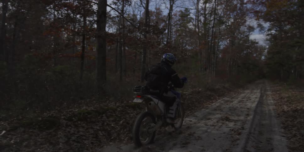 A person on a blue bike rides on a dirt trail