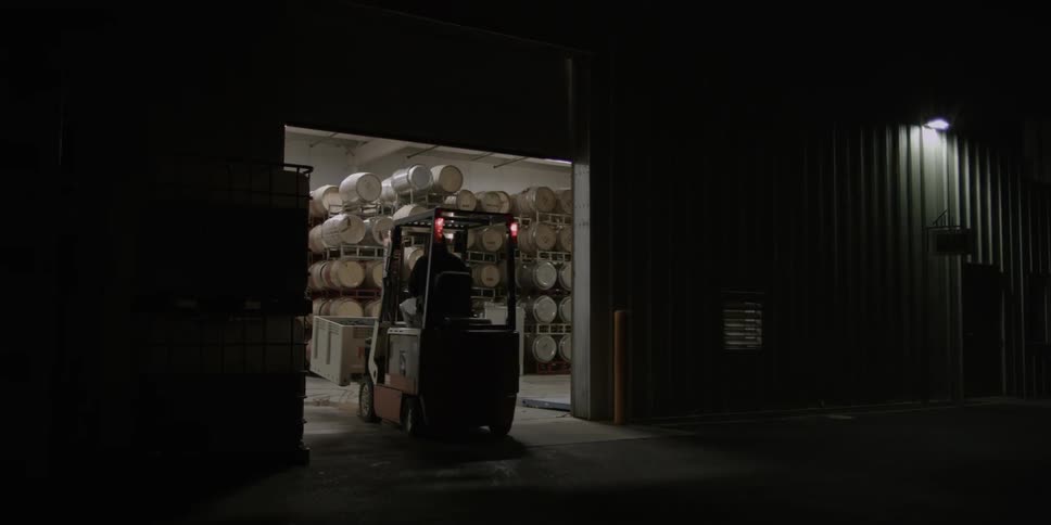 A forklift goes into a warehouse at night