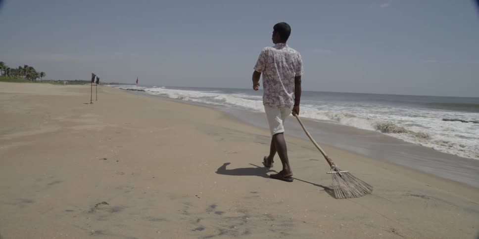 Man carrying a rake walking on the beach