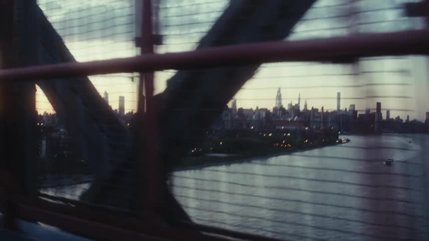 Running view of a city skyline through the metal framework of a bridge