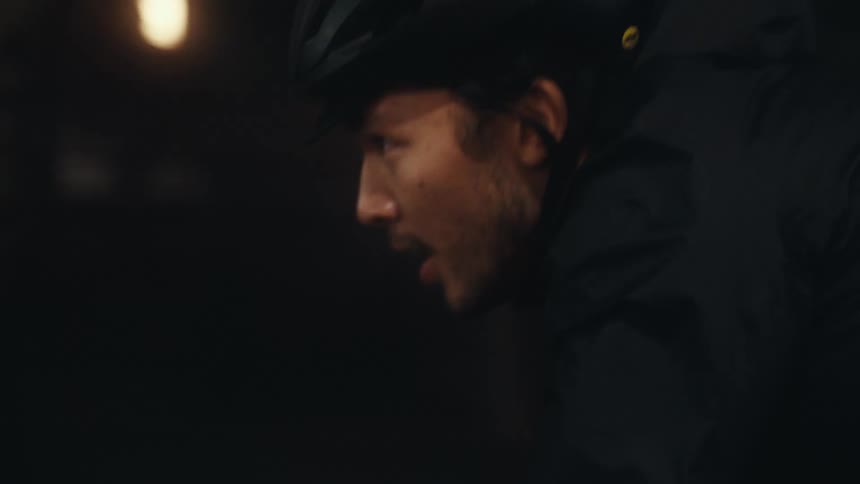 A man with a helmet and coat is riding a bicycle