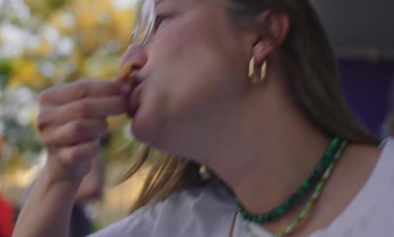A young girl with glasses is eating food and dips it in sauce to eat