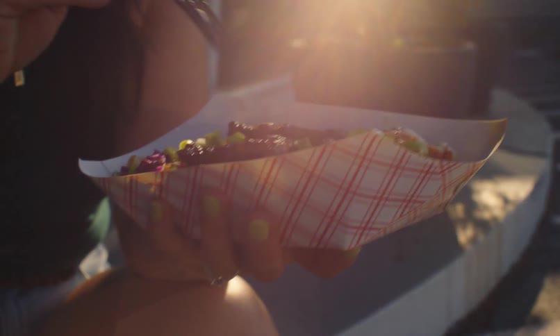 Closeup of hands holding a tray of food and eating with a fork