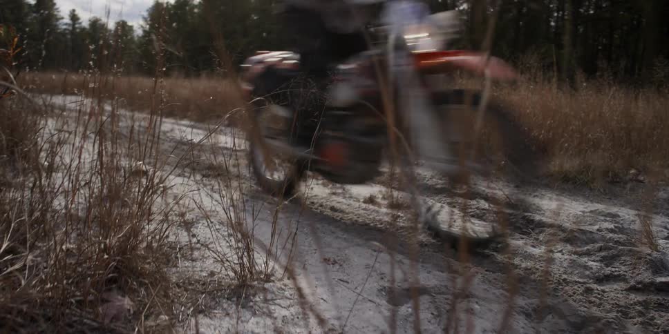 A man rides a motorcycle on a dirt path