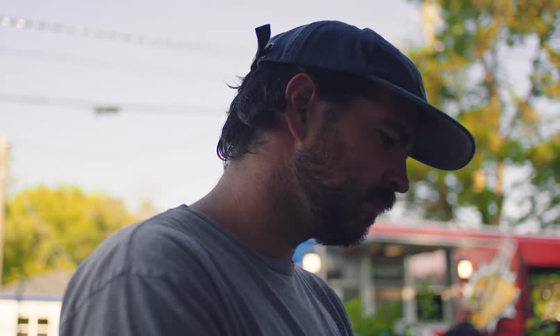 Side portrait of a man with a beard and a blue cap in an outdoor setting