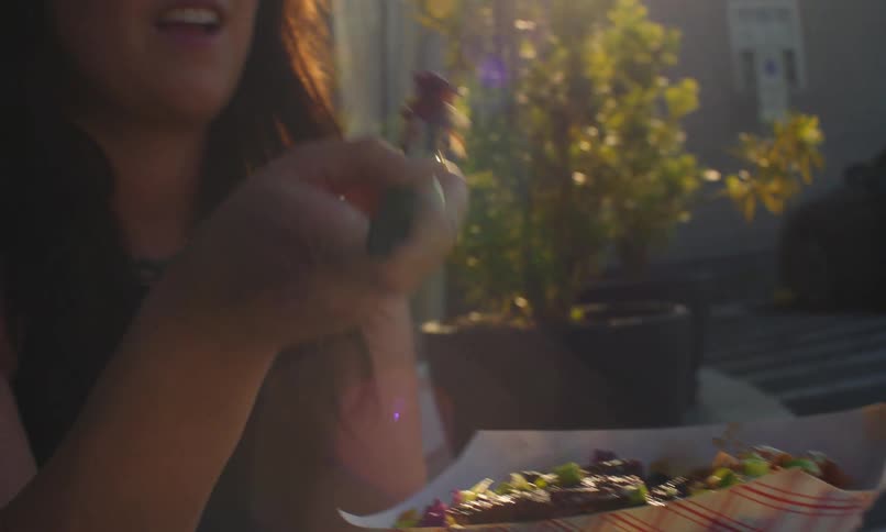 Woman eating food with a fork outdoors