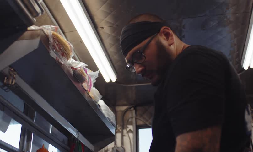 An employee of a food truck speaks while working