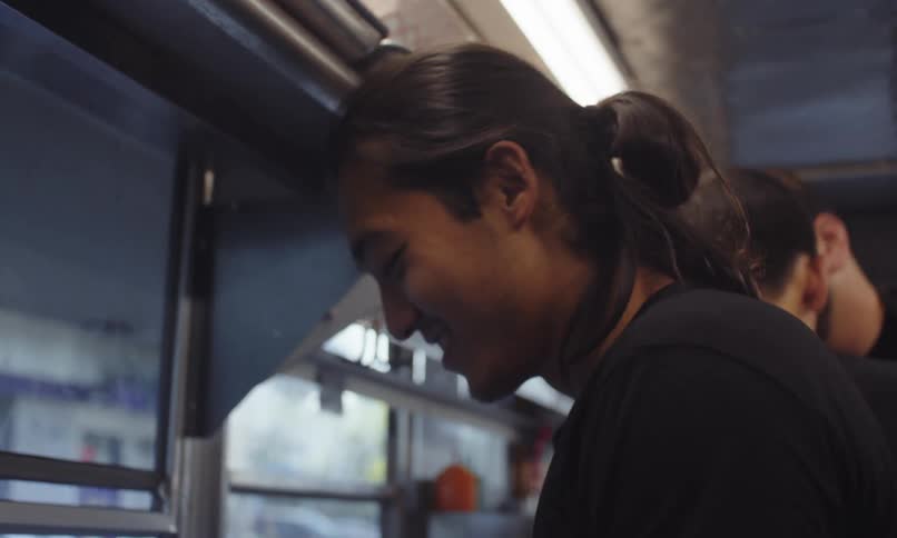 Three food truck workers put orders together and interface with customers