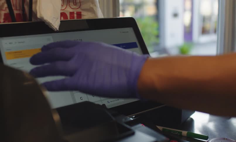 A person wearing a purple glove interacting with a digital payment terminal