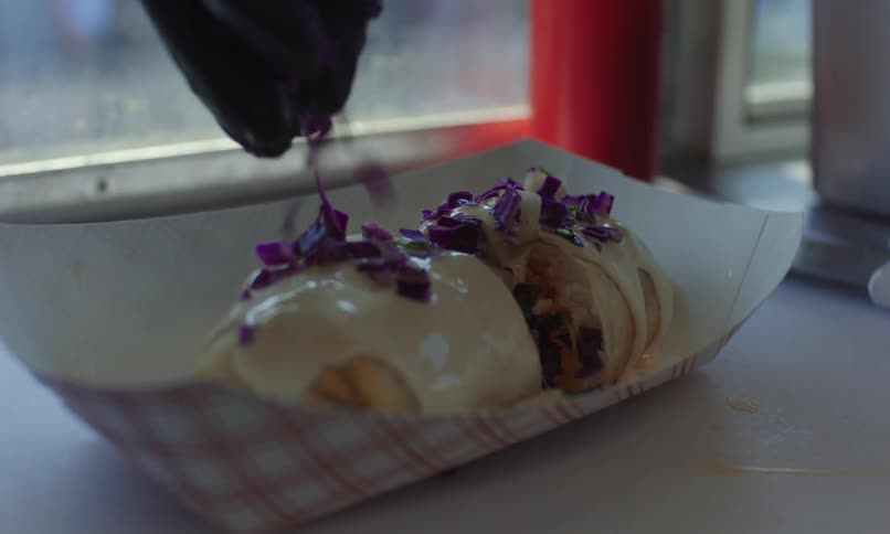 Gloved hand preparing and garnishing a dish with shredded vegetables