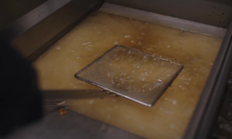 Frying basket submerged in hot oil in a deep fryer