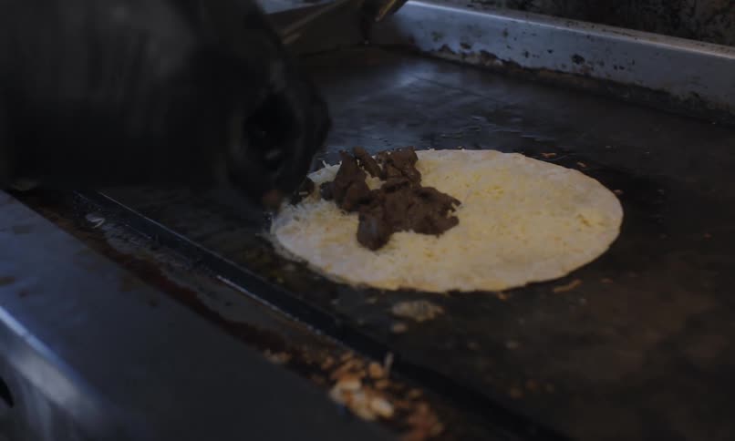 A man in a mobile kitchen preparing a tortilla