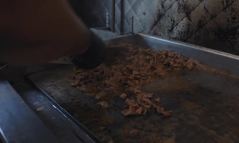 A man is cooking meat in the food truck