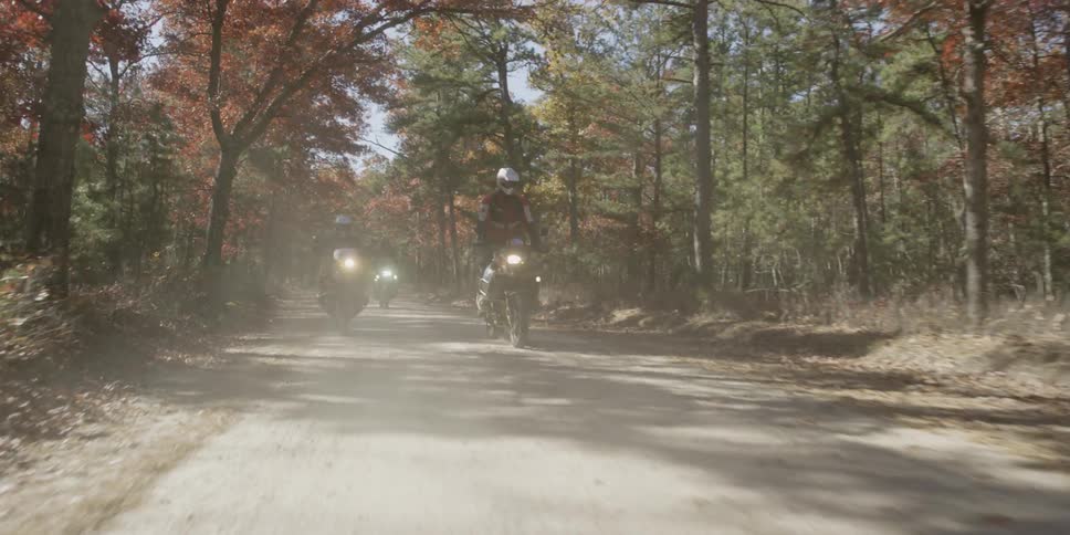 Three bikers are riding on a dirt road