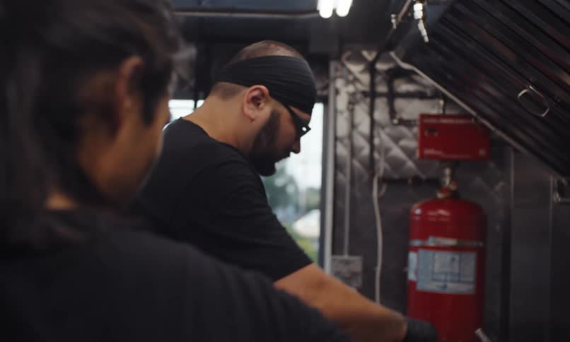 Two men are talking and cooking in the food truck