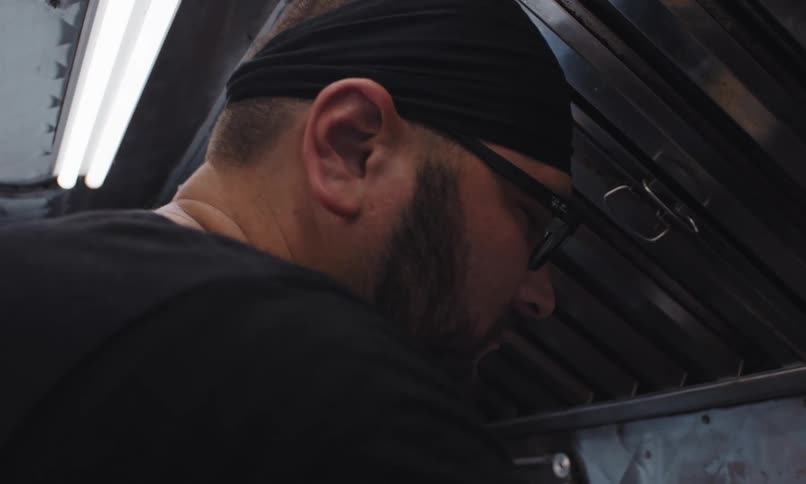 A man with glasses and a beard works in the kitchen of a restaurant