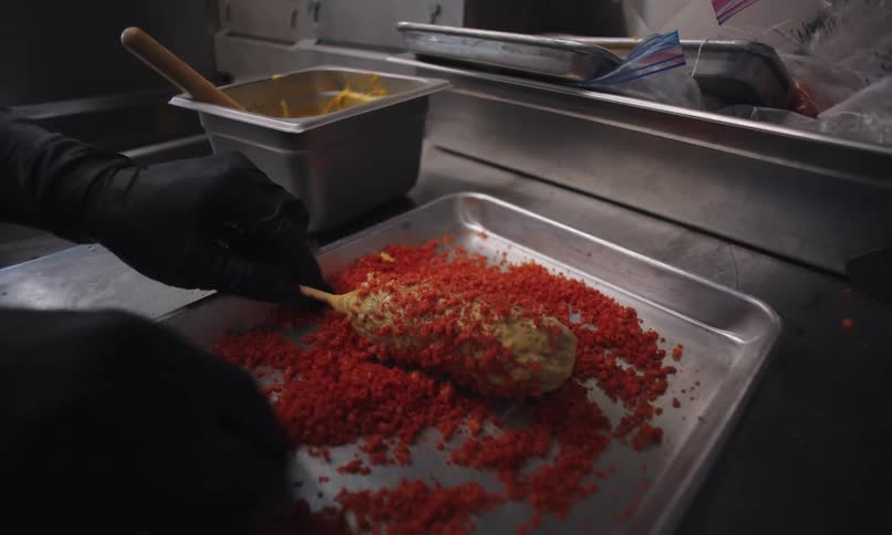A person puts spices on food in a food truck