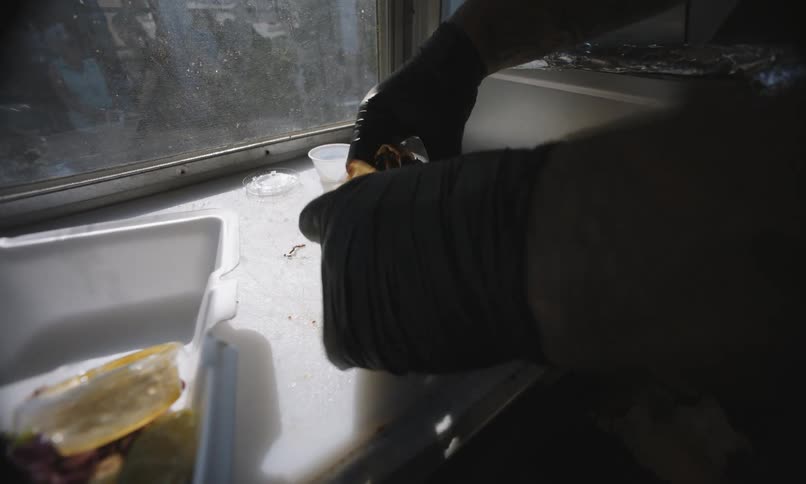 Food is being cut and put in a container in the food truck