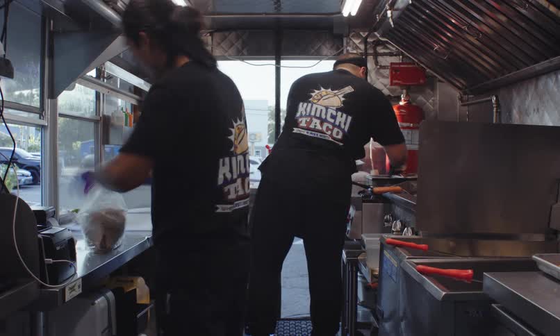 Two people inside a food truck are preparing food