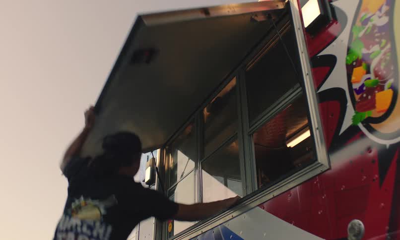 A man jumps to close a panel of a stall and there is a logo with writing in white