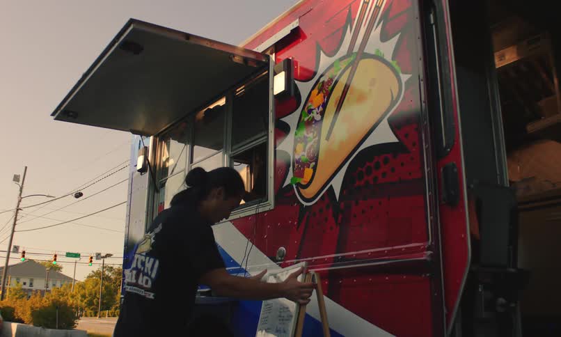 Food truck worker setting up with a colorful tacothemed design on the truck