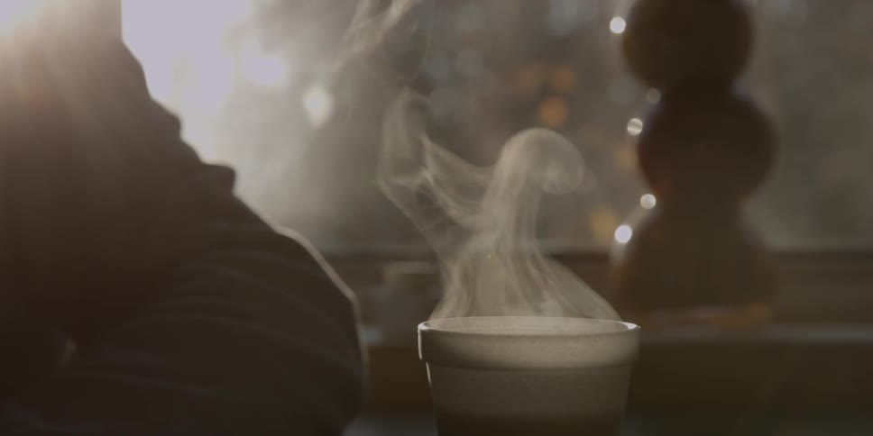 Steam is rising from a coffee in a styrofoam cup