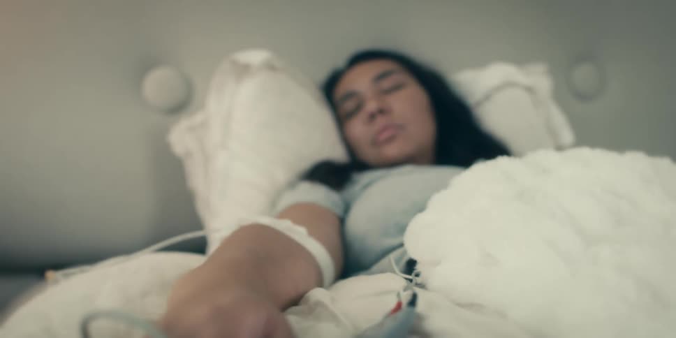 Woman with a pulse oximeter and an iv sleeping in a bed at home