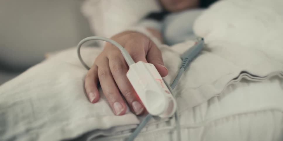 Female patient sleeps while her heart rate and oxygen level are monitored