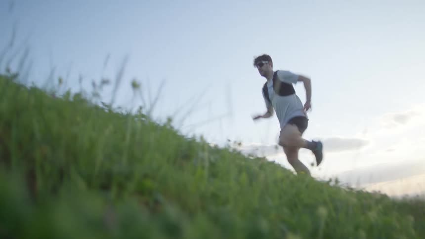 A white man runs up a grassy hill