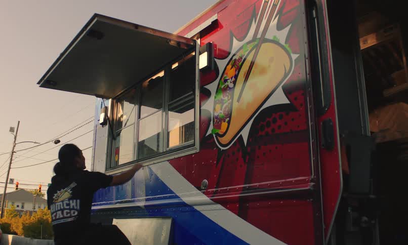An employee of a food truck closes the windows up