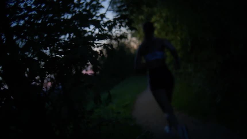 A woman runner runs down the pathway at dawn
