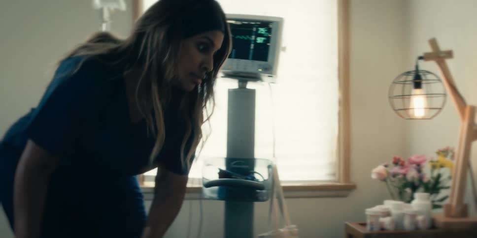 Nurse writing down on a patients chart with a heart monitor in the background