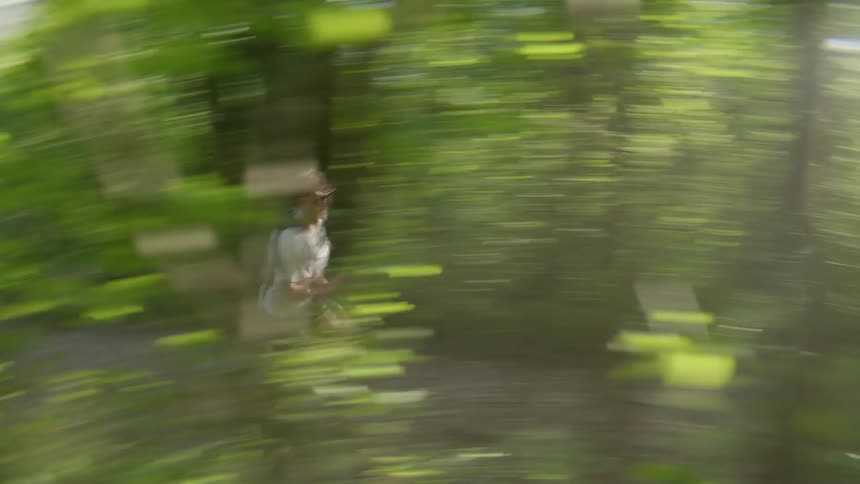 A man is running quickly on a path in the middle of a forest of green vegetation