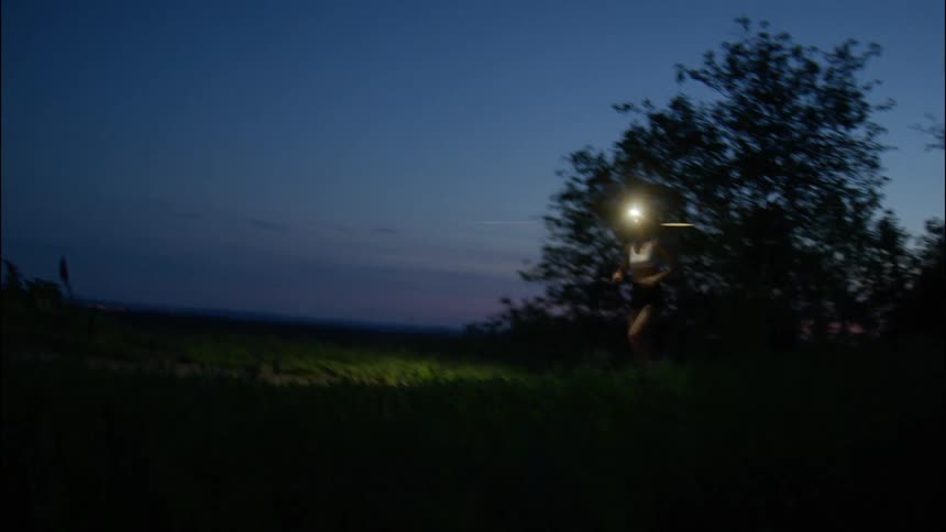 Woman running at dusk while wearing a headlamp