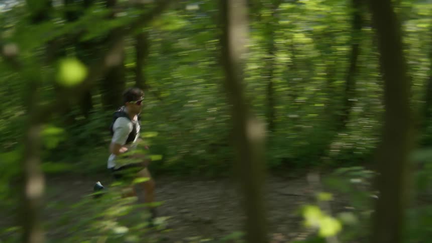 Man runs along the path through the forest on a sunny summer day