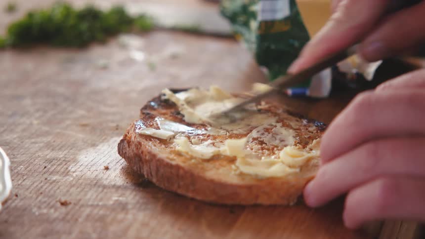 Butter being spread on a baked bread
