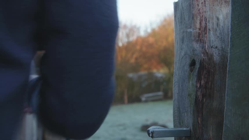 Man opens and closes gate to enter a pasture with a frost covered ground