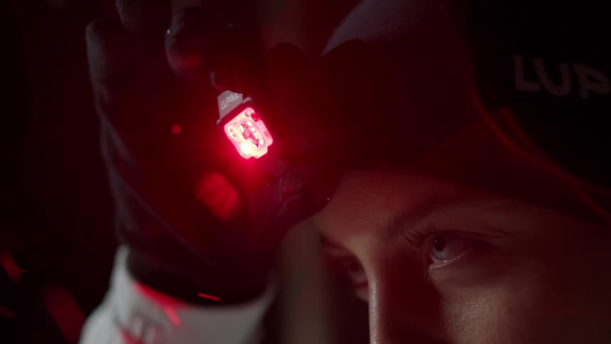 Woman changes color of headlamp from red to white while she stands outdoors on a snowy night
