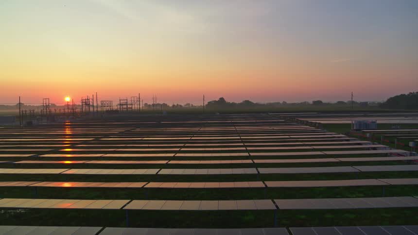 Panorama of solar panels on an agricultural field and a reddish sunset on the horizon