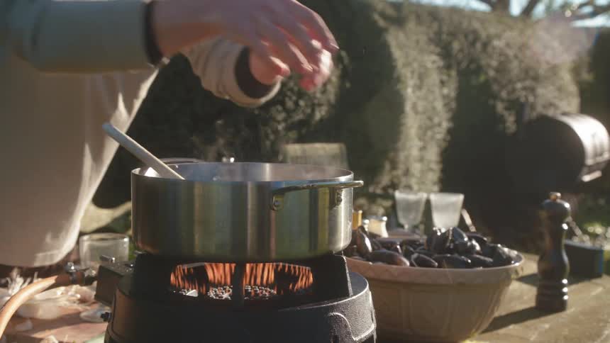 Mussels being placed inside a pan with the heat on